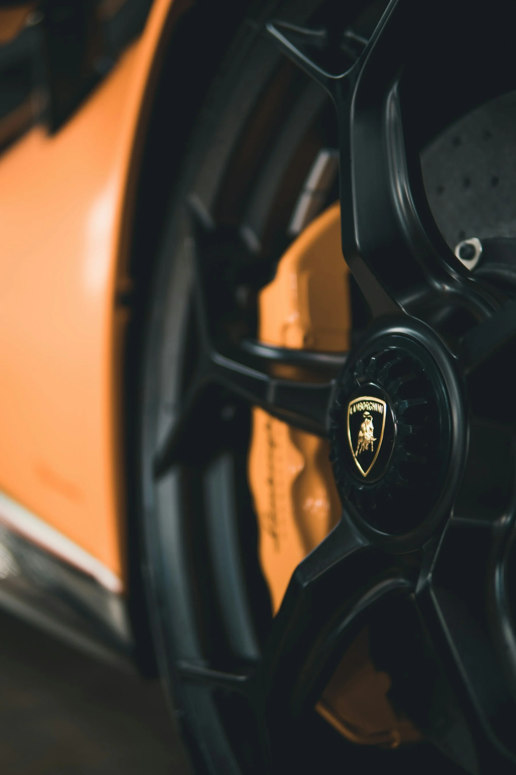 Detalhe da roda preta de um carro esportivo laranja
